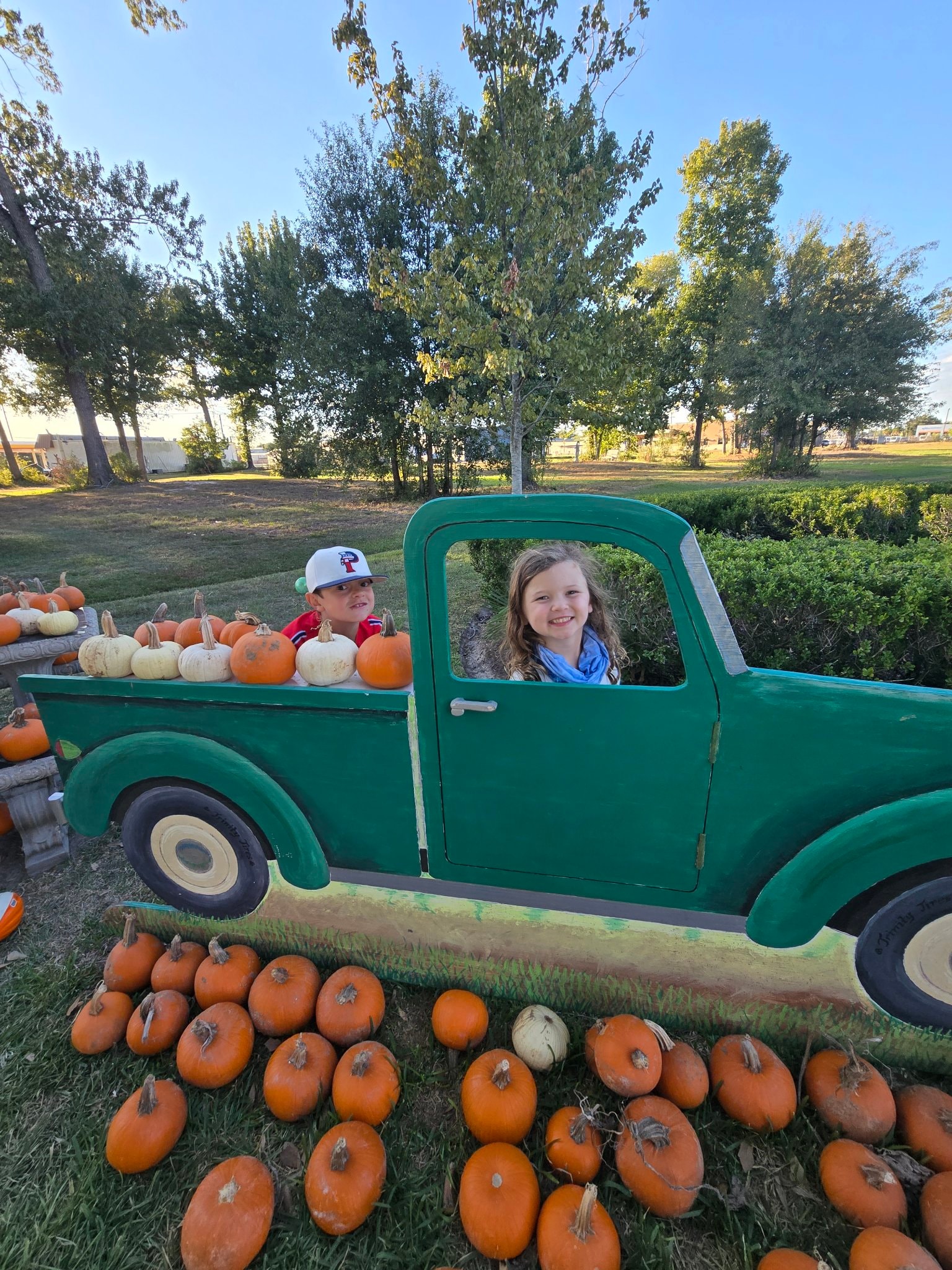 Kids posing in a green vintage truck prop at the pumpkin patch